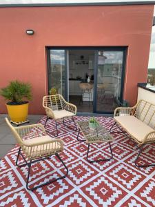 a patio with three chairs and a rug at Le Rooftop d’Isa in Colombelles