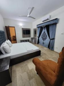 a bedroom with a large bed and a chair at Hotel Capital one in Karachi