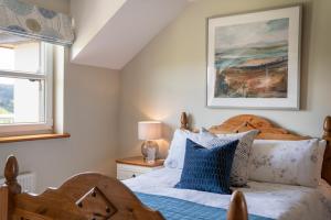 a bedroom with a wooden bed with blue pillows at Killoran House in Dervaig