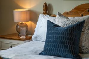 a bed with blue and white pillows and a lamp at Killoran House in Dervaig