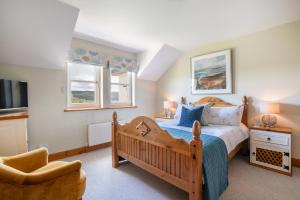 a bedroom with a wooden bed and a chair at Killoran House in Dervaig