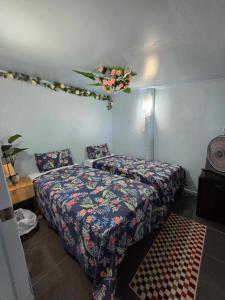 Titikawekaにある2rangi Beach Homestay at Mirimiri Spaのベッド2台が備わる客室で、壁に花を飾っています。
