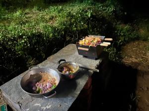 two pans of food sitting on a stone table at Woodside Traditional Homestays in Nagar
