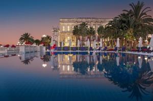 a building with a pool in front of a building with palm trees at Çırağan Palace Kempinski Istanbul in Istanbul
