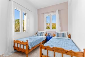 two beds in a room with two windows at Villa Santa Marina in Spetses