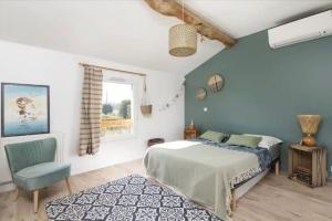 a bedroom with a bed and a chair and a window at Logement familial « Le Ribet » in Saint-Étienne-de-Tulmont