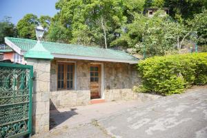 uma pequena casa de pedra com um portão verde em Classiyo Green Mount Resort em Chinnakanal