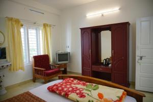 um quarto com uma cama, uma televisão e uma cadeira em Classiyo Green Mount Resort em Chinnakanal