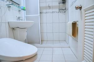 La salle de bains blanche est pourvue de toilettes et d'un lavabo. dans l'établissement The Wind B&B, à Budai