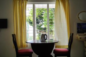 uma mesa com uma chaleira de chá em frente a uma janela em Classiyo Green Mount Resort em Chinnakanal