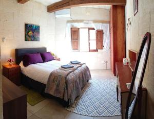 a bedroom with a bed with purple pillows and a table at Arthome - guest rooms in Għarb