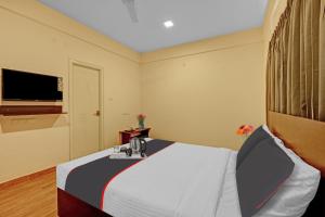 a hotel room with a bed and a flat screen tv at Super OYO Manyata Stay-In in Bangalore