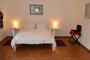 1 dormitorio con 1 cama blanca y 2 velas en 2 mesas en Stefania Guest House, en Giba
