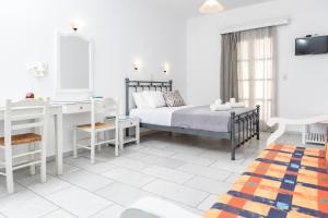 a white bedroom with a bed and a desk and a mirror at Depis studios & apartments in Naxos Chora