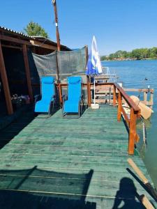 a dock with chairs and an umbrella on the water at Ada Bojana - Kucica Djakonovic in Ulcinj