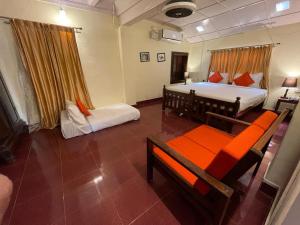 a bedroom with two beds and a table and a couch at Avadale Coorg - Stag Groups Not Allowed in Ammatti