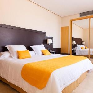 een grote slaapkamer met een groot bed met gele kussens bij HOTEL PUERTA DE SAHAGUN in Sahagún