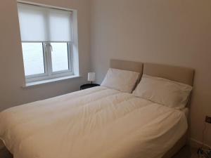 un letto bianco in una camera da letto con finestra di Peaceful 2 Bed Townhouse, Close to City Centre a Reading