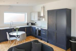 uma cozinha com armários azuis e uma pequena mesa e uma cozinha com uma janela em Peaceful 2 Bed Townhouse, Close to City Centre em Reading