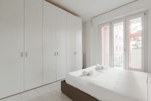 ein weißes Schlafzimmer mit einem großen Bett und einem Fenster in der Unterkunft Corvetto M3 - Bright Apt. with balcony! in Mailand