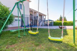 a playground with swings in the yard of a house at Villa Toni - Adriatic Luxury Villas in Zadar