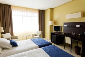 サアグンにあるHOTEL PUERTA DE SAHAGUNのベッド、デスク、コンピュータが備わるホテルルームです。