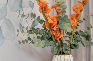 biała waza z pomarańczowymi kwiatami w obiekcie Bright Apartment with Spacious Balcony and Air Conditioning by Renters w mieście Rzeszów