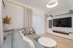 a living room with a gray couch and a table at Bright Apartment with Spacious Balcony and Air Conditioning by Renters in Rzeszów