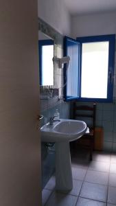 a bathroom with a sink and a mirror and two windows at Hotel Baia Cea in Bari Sardo