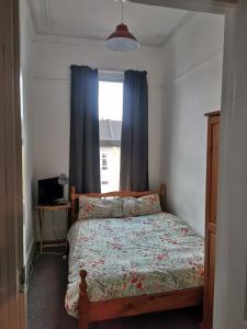 1 dormitorio con 1 cama con cortinas azules y ventana en Freedom Park Villa room 3 en Plymouth