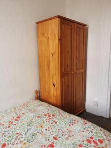 1 dormitorio con armario de madera junto a la cama en Freedom Park Villa room 3 en Plymouth