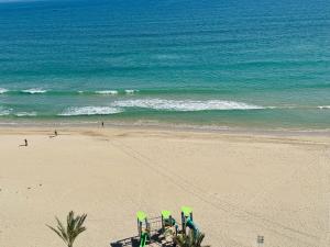uma praia com cadeiras verdes e o oceano em Vistas al Mar, Piscina y Playa em Alicante
