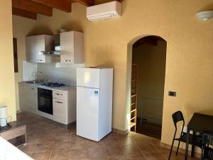 a kitchen with a white refrigerator and a table at Borgo Spiaggia Isola Rossa in Isola Rossa