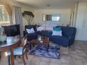 a living room with a blue couch and a bed at Shells on the Beach in Sea View