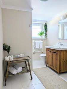 ein Badezimmer mit einem Waschbecken, einem WC und einem Tisch in der Unterkunft SB Apartment in Kołobrzeg