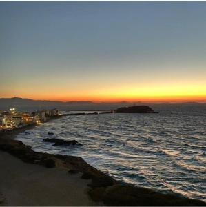 um pôr-do-sol sobre o oceano com uma praia de areia em Irida Holiday Home em Naxos Chora