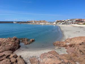 a beach with rocks and the water and buildings at Borgo Spiaggia Isola Rossa in Isola Rossa