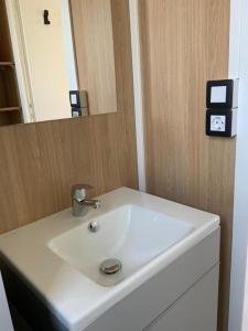 een badkamer met een witte wastafel en een spiegel bij Camping Oasis Middelkerke Louisiane I, II, III, IV in Oostende