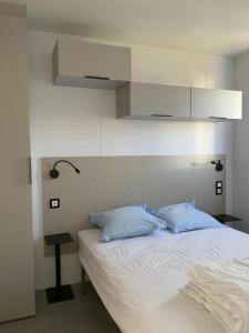 een slaapkamer met een wit bed en 2 blauwe kussens bij Camping Oasis Middelkerke Louisiane I, II, III, IV in Oostende