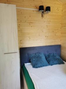 a bed with blue pillows on it in a room at Domki Pod Szyszką in Rowy