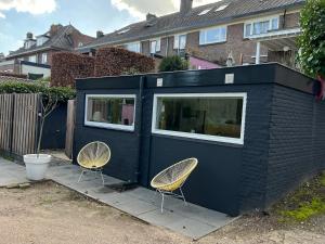 a black building with two chairs in front of it at Naar Ineke in Doesburg