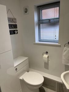 a white bathroom with a toilet and a sink at Modern 2 Berth Seaside Studio Apartment On Ground Floor In Hemsby, Ref 99011ws in Great Yarmouth