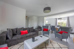 uma sala de estar com um sofá cinzento e almofadas vermelhas em Villa Elaïa maison Familiale Omaha Beach em Saint-Laurent-sur-Mer