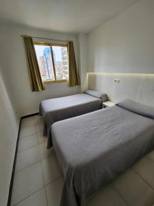 Habitación con 3 camas y ventana en Apartamentos Maria Victoria, en Benidorm
