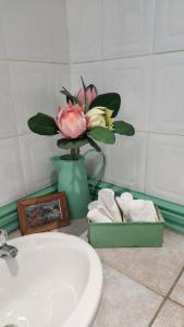 a bathroom with a sink and a vase with a flower at Tripple N Guest Lodge in Ladybrand