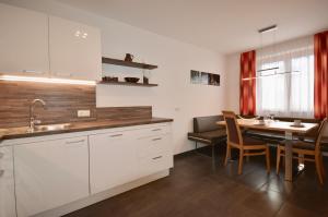 a kitchen with white cabinets and a dining table at Ferienwohnung Sonnenhang in Nußdorf