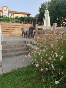 a patio with two chairs and an umbrella and some flowers at Villa Argentine T2 classé 2* thème cosy in Dax +3 photos