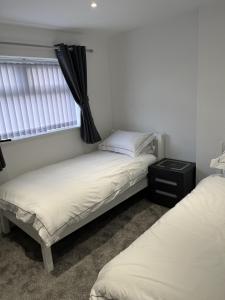 two twin beds in a room with a window at Beautiful 4 Berth Seaside Apartment On Ground Floor In Hemsby, Ref 99010fh in Great Yarmouth