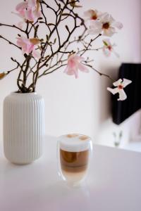 a white vase with flowers and a cup of coffee at Apartament Bimba - Free Parking in Poznań