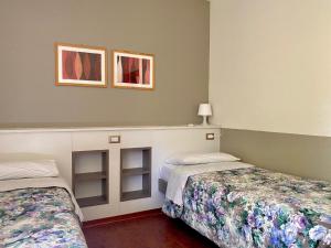 sypialnia z 2 łóżkami i 2 zdjęciami na ścianie w obiekcie Unabhaengige Wohnung in Sirmione mit Eigener Terrasse w Sirmione